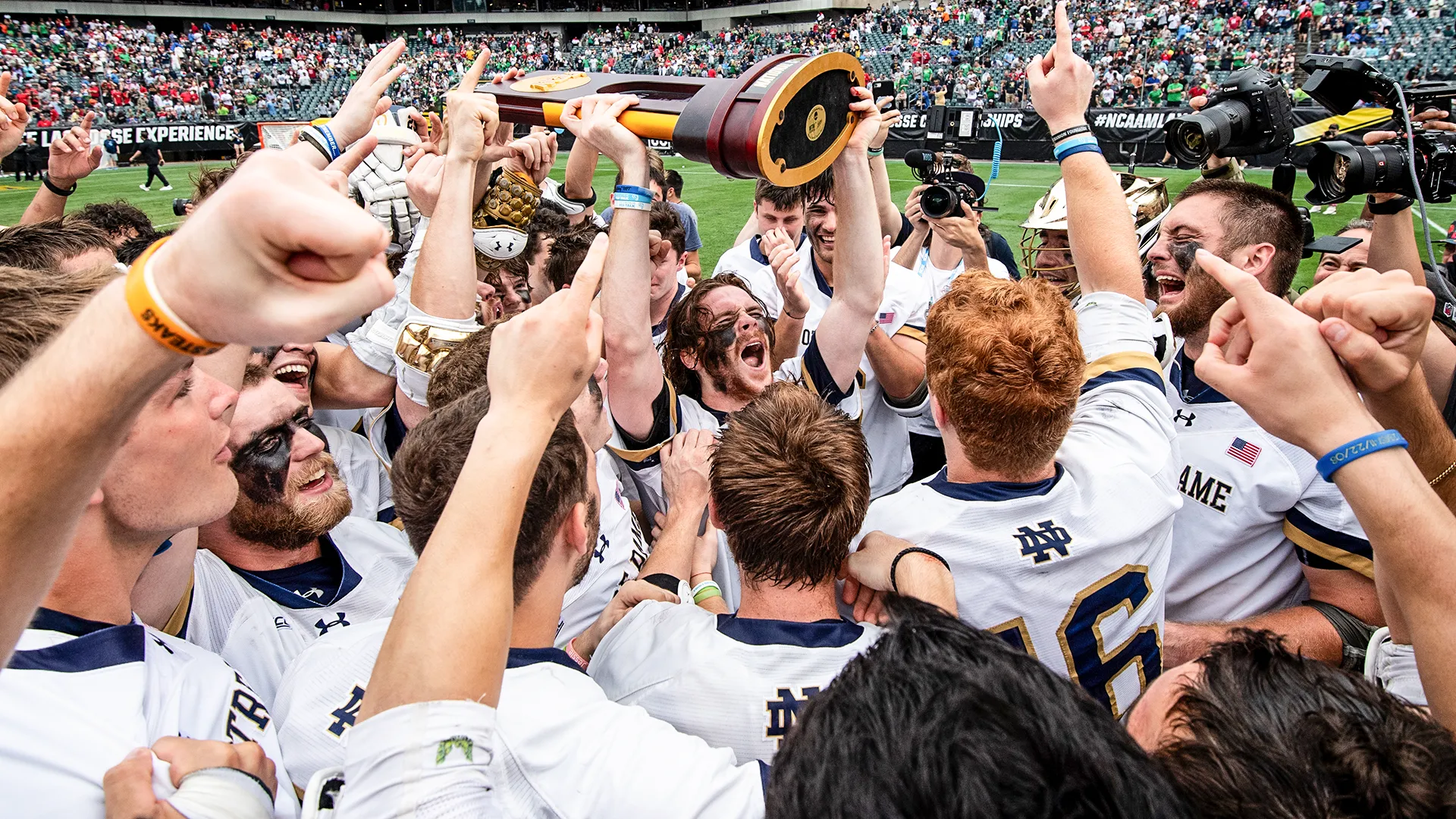 Notre Dame's Pat Kavanagh hoists the walnut and bronze trophy surrounded by teammates celebrating at Lincoln Financial Field in Philadelphia.