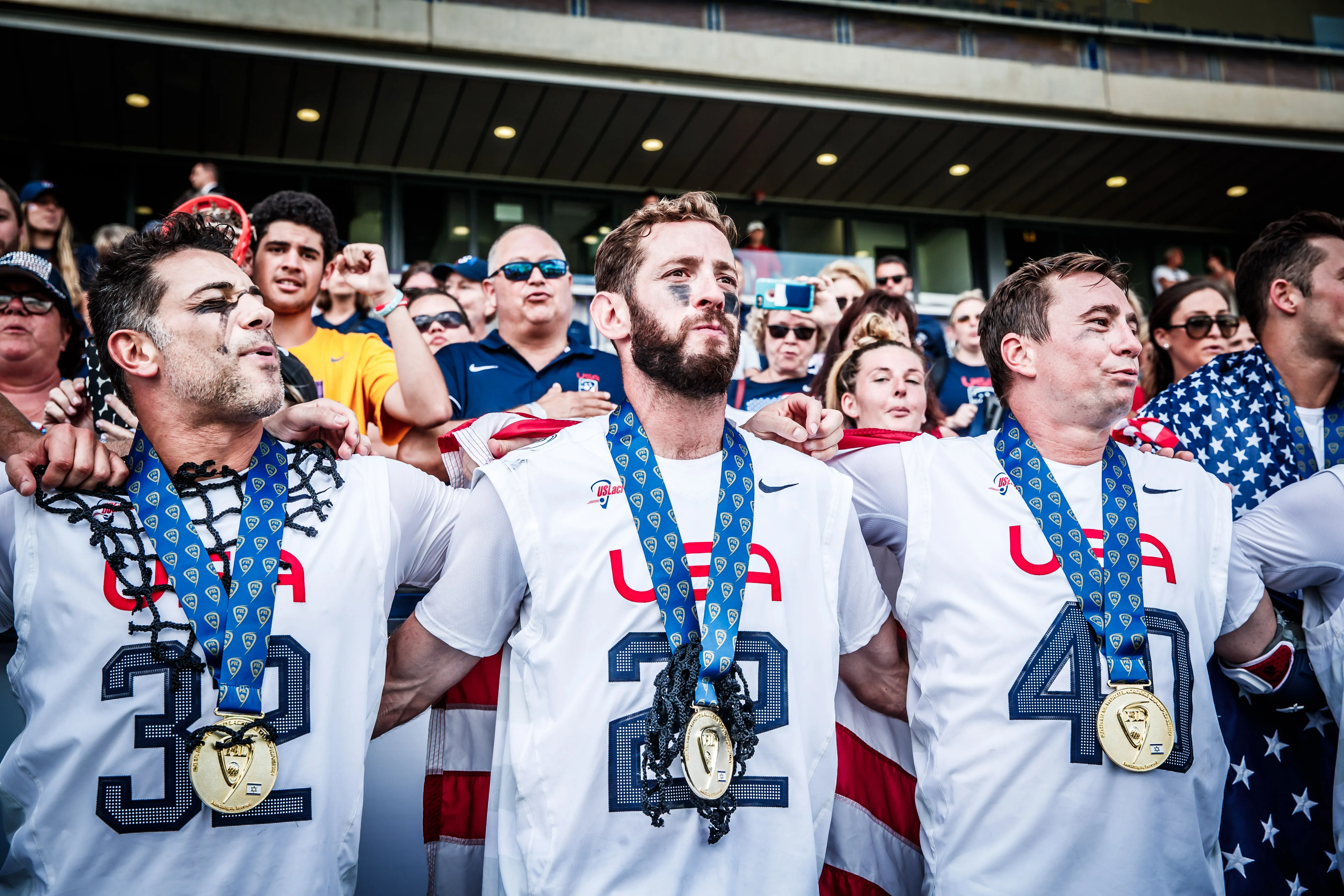 Ned Crotty (22) links arms with Greg Gurenlian (32) and Matt Danowski (40) singing the national anthem with gold medals hanging from their necks after the 2018 FIL Men's World Championship final at Netanya Stadium in Israel.