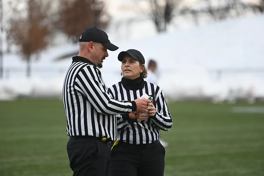 Picture of two officials huddled up during a break in a lacrosse game.