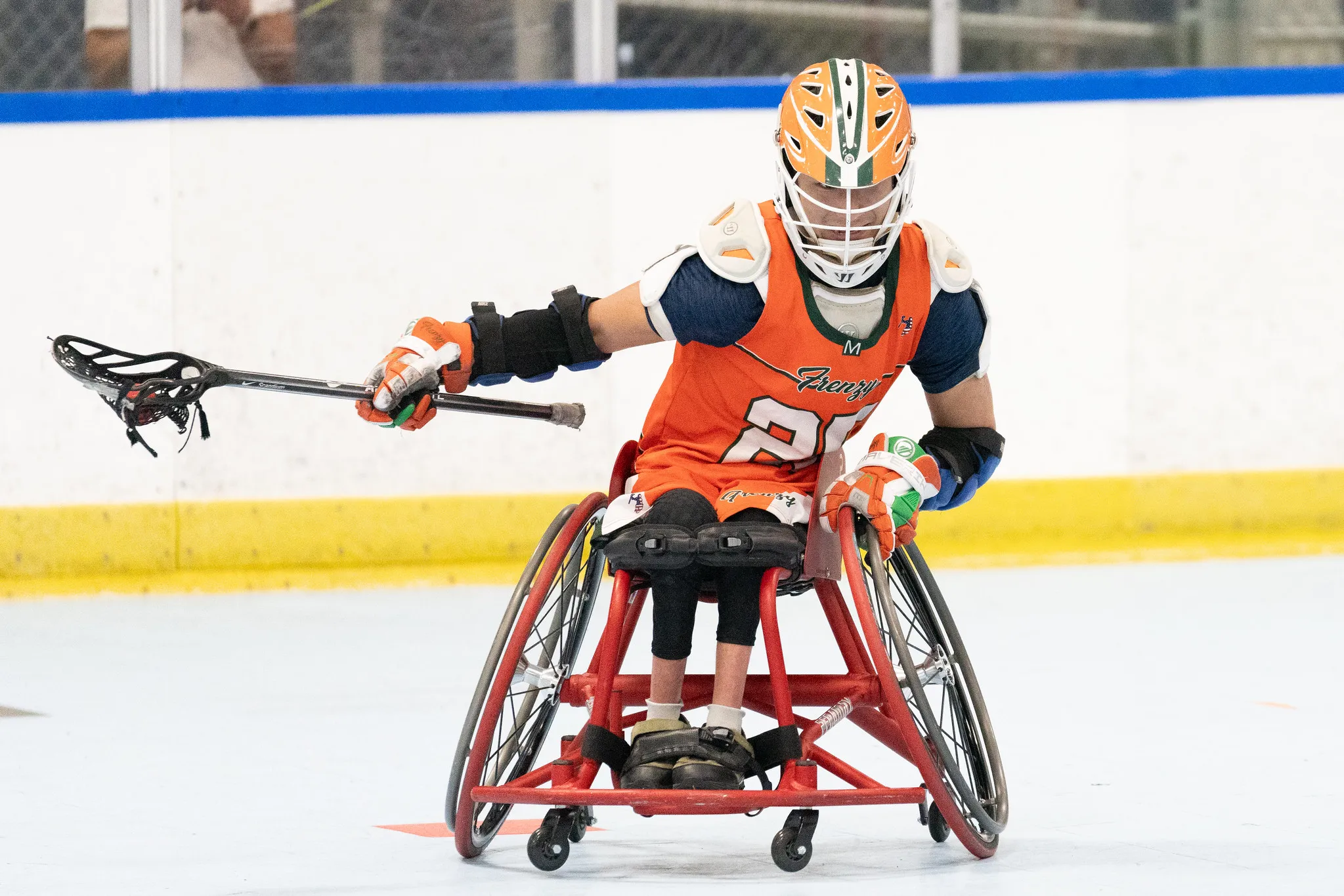 a wheelchair lacrosse player dodges with one hand on their stick