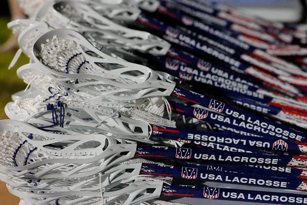 Rows of USA Lacrosse sticks with USA Lacrosse printed on the blue shafts