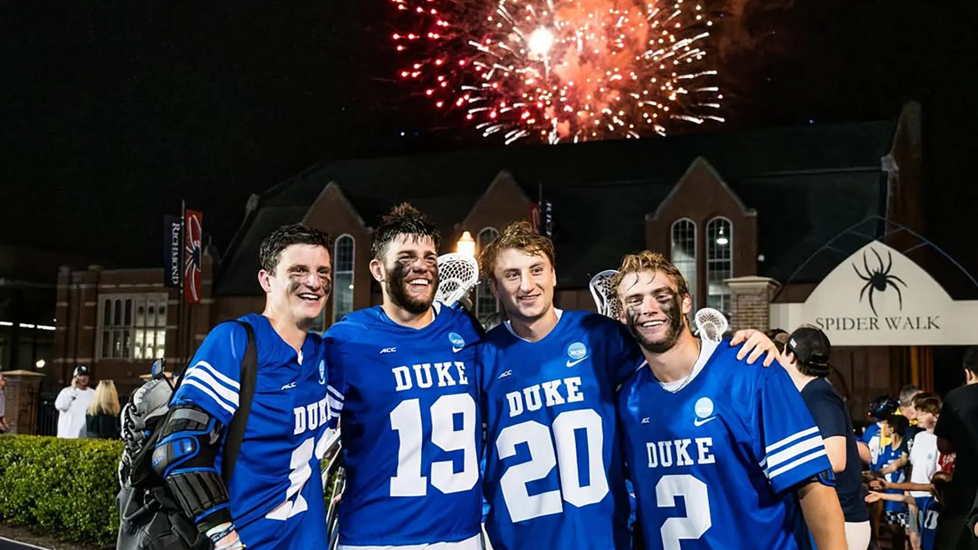 Duke players huddle as fireworks go off in the background