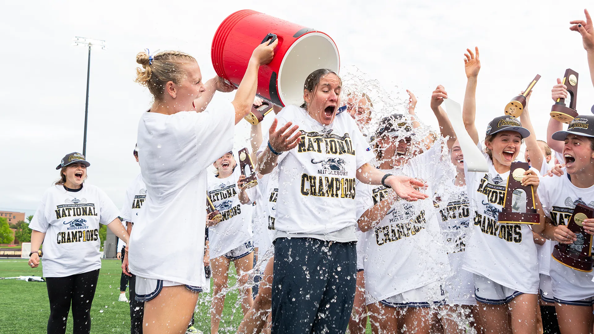 Middlebury head coach Kate Livesay gets drenched with water following the championship win