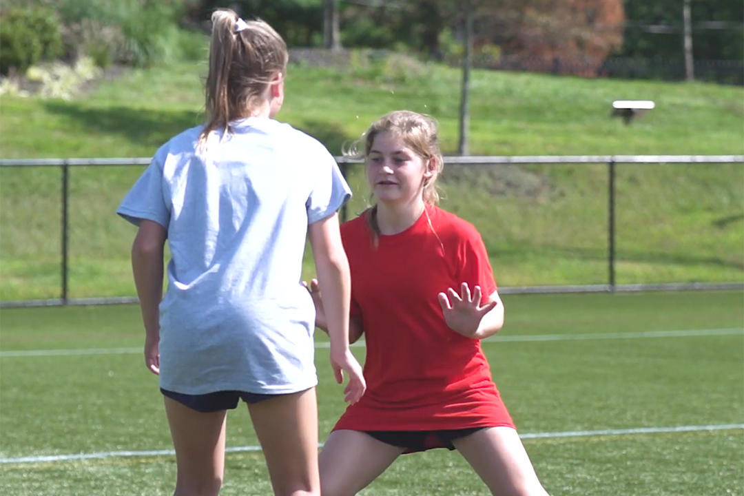 Young girl positioning herself to play defense in lacrosse