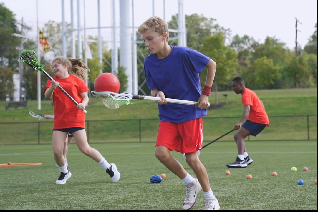 photo of a boy scooping an oversized ball with his lacrosse stick