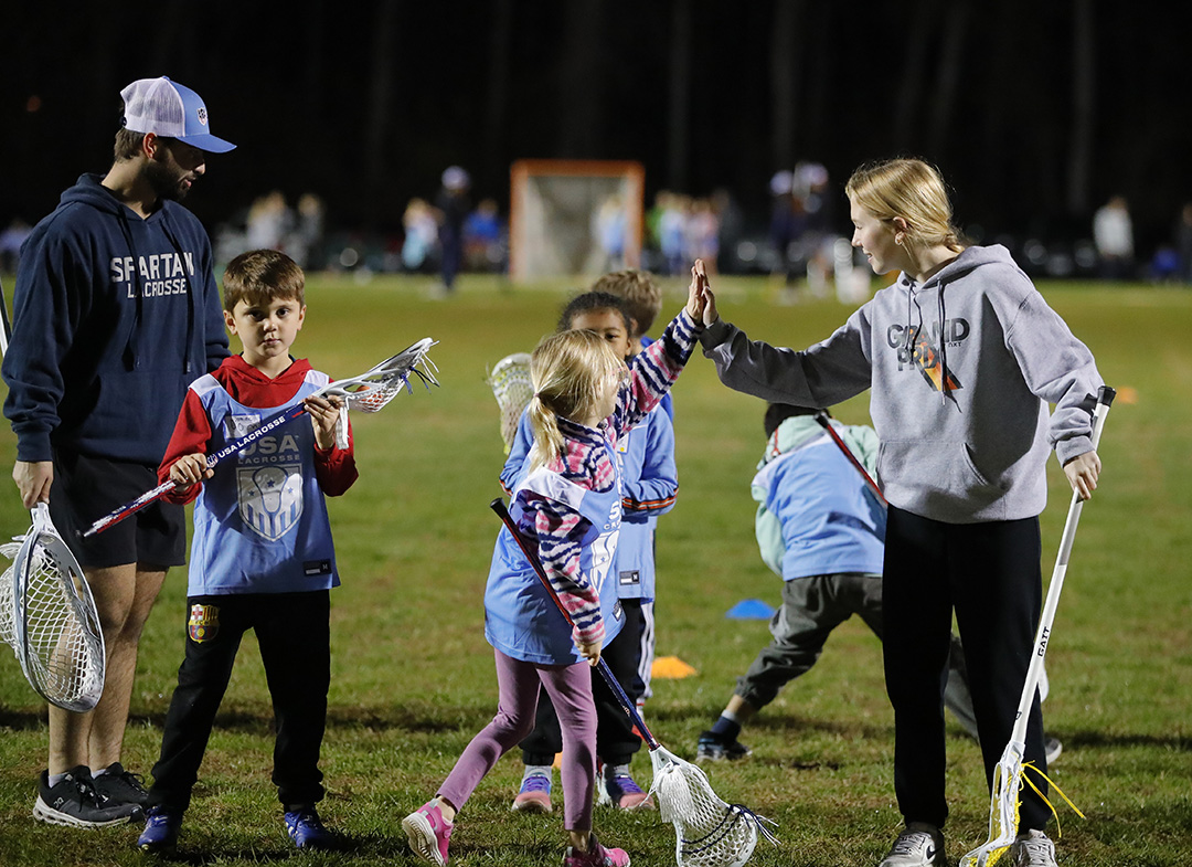 A young girl high fives her coach during a National Celebrate Lacrosse Week clinic