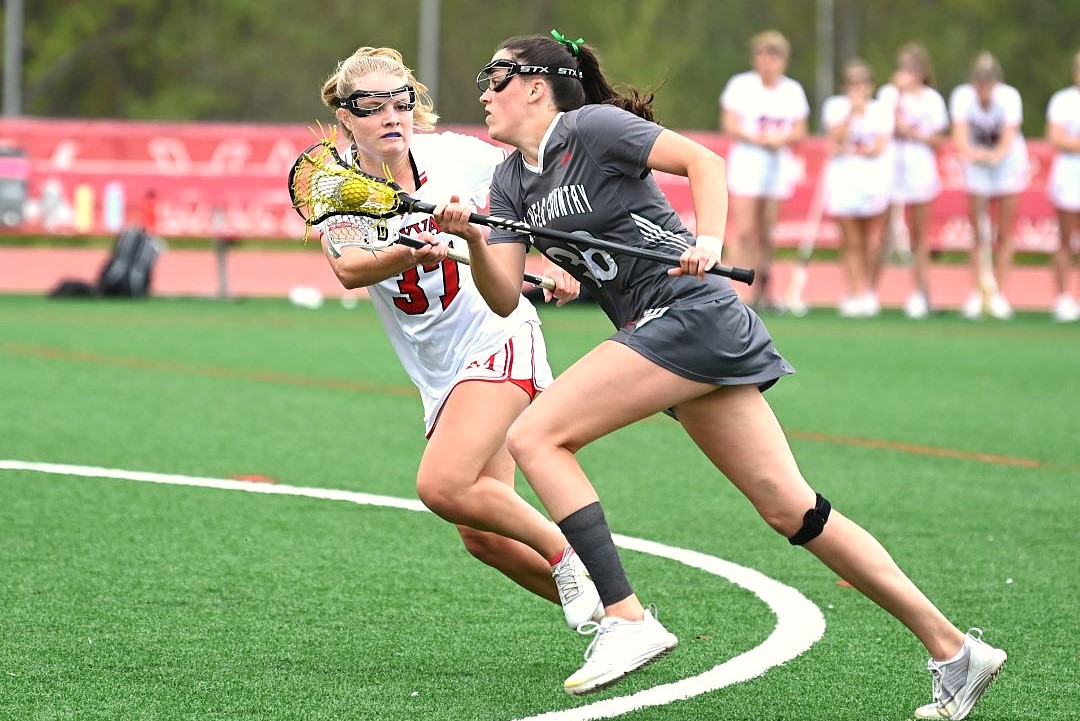 two girls lacrosse players running next to each other