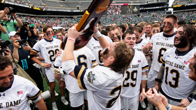 Notre Dame players gather around the NCAA championship trophy.