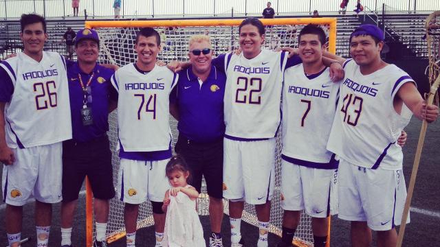 Haudenosaunee men's lacrosse coach Mark Burnam stands with players following a world championship game.