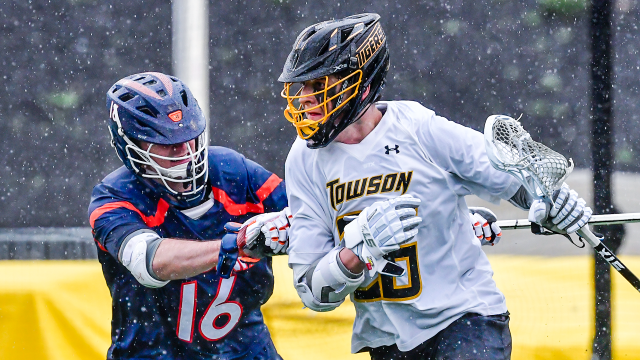 Towson lacrosse player Joaquin Villagomez carries the ball toward the goal against a Virginia defender during an early 2024 game