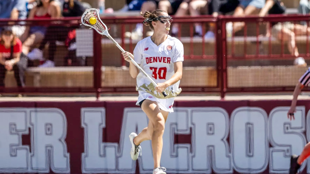 Denver defender Megan Klingenberg cradling the ball with her lacrosse stick running up the field at Peter Barton Lacrosse Stadium