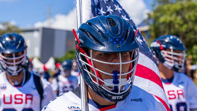 Zach Hayashi carries the American flag leading the U.S. U20 men's lacrosse team onto the field for the championship game in 2025.