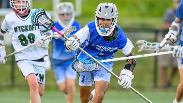 A rec youth lacrosse player chases a ground ball
