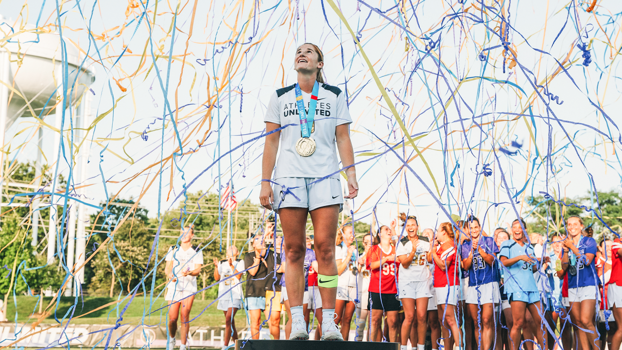 Sam Apuzzo surrounded by confetti as she stands on the champion's pedestal following the Athletes Unlimited season finale at USA Lacrosse in Sparks, Md.