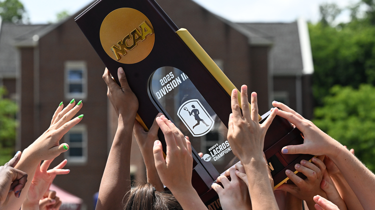 Middlebury women's lacrosse players hoist the 2025 NCAA Division III championship trophy at Roanoke College's Kerr Stadium in Salem, Va.