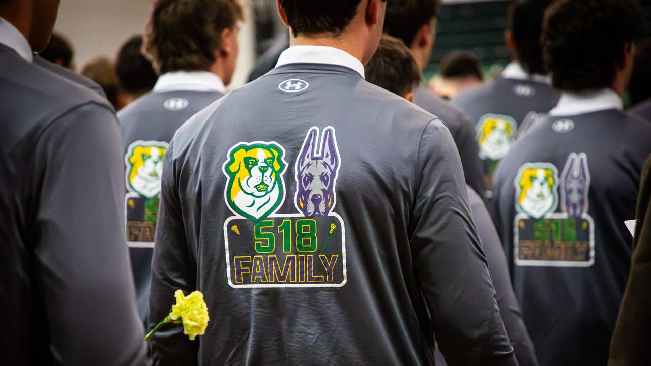 Siena men's lacrosse players with yellow roses and shirts that read "518 Family" with UAlbany and Siena logos at Liam Gleason's memorial service