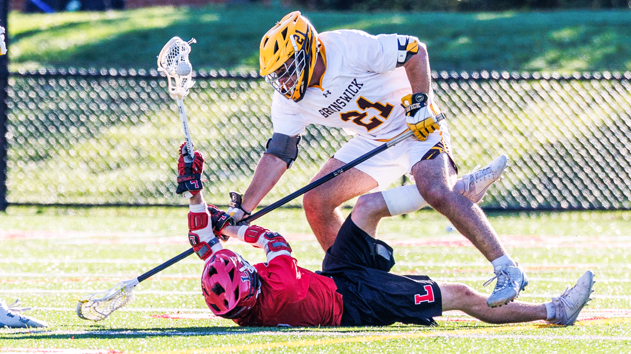 A Brunswick (Conn.) defenseman looks to strip the lacrosse ball from a fallen Lawrenceville (N.J.) player