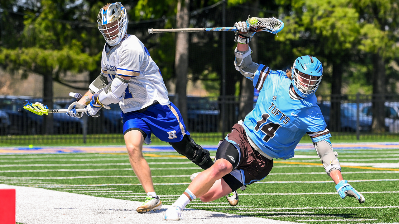 Garrett Kelly of Tufts lacrosse maintains possession of the ball while falling near the sideline during a game against Hamilton.