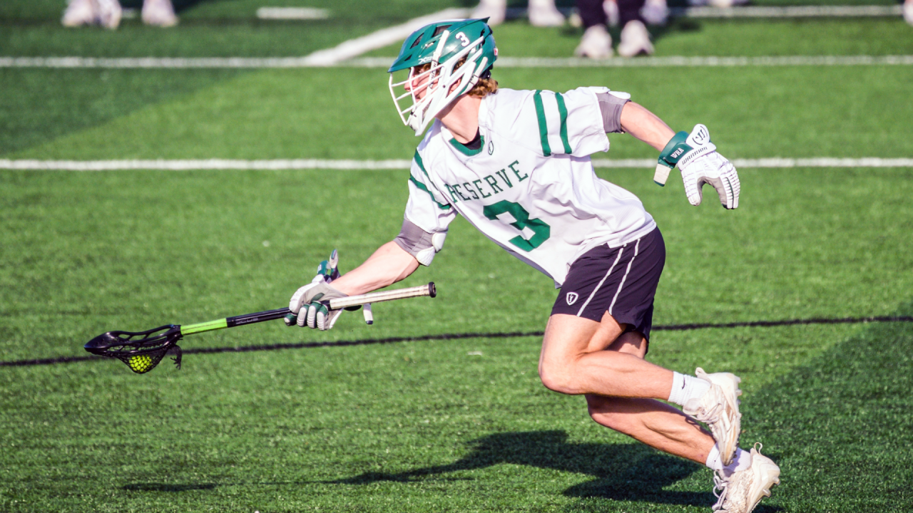 A Western Reserve (Ohio) lacrosse player running with ball up the field and stick extended