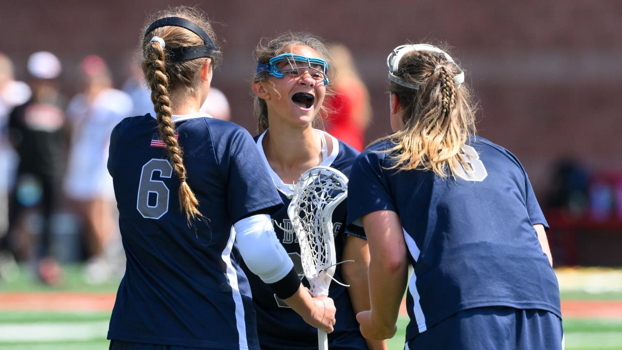 Huntington (N.Y.) girls' lacrosse players huddle to celebrate after scoring a goal in the New York Class A final at Cortland