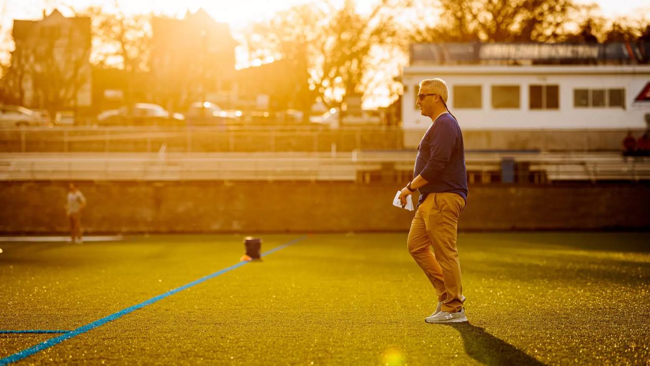 Drew Kelleher walks on an empty lacrosse field as the sun sets
