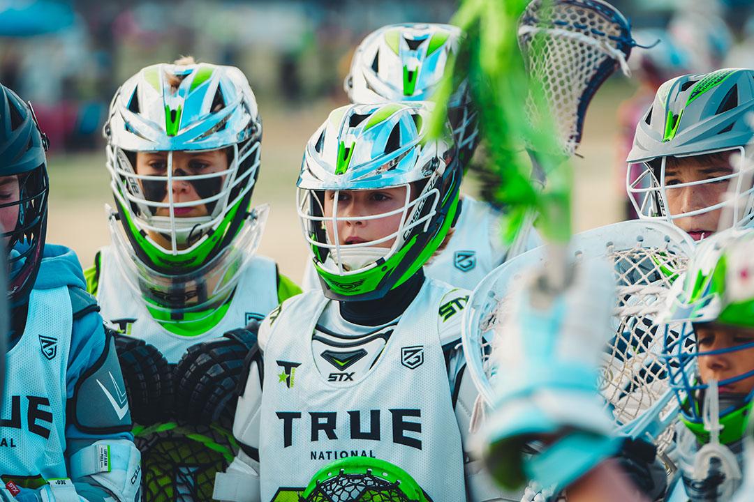 True Lacrosse boys youth lacrosse players lined up in a team huddle